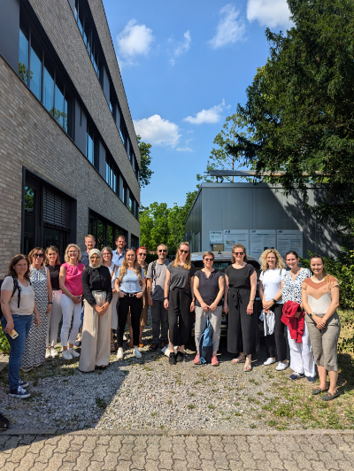 große Gruppe von PErsonen steht auf einer Grünfläche und schaut entspannt und zufrieden in die Kamera. Grade haben sie Technologien für die Energywende bei der Führung durch das Energy Smart Home Lab erlebt.
