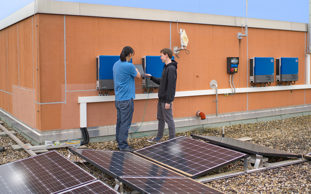 Wissenschaftler auf einem Dach mit PV-Anlage