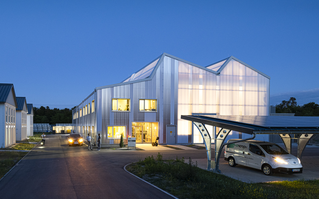 SEnSSiCC-Halle bei Dämmerung, davor ein Solarcarport für die Energiewende und links das Living Lab Reallabor für die Forschung an intelligenten Energiesystemen